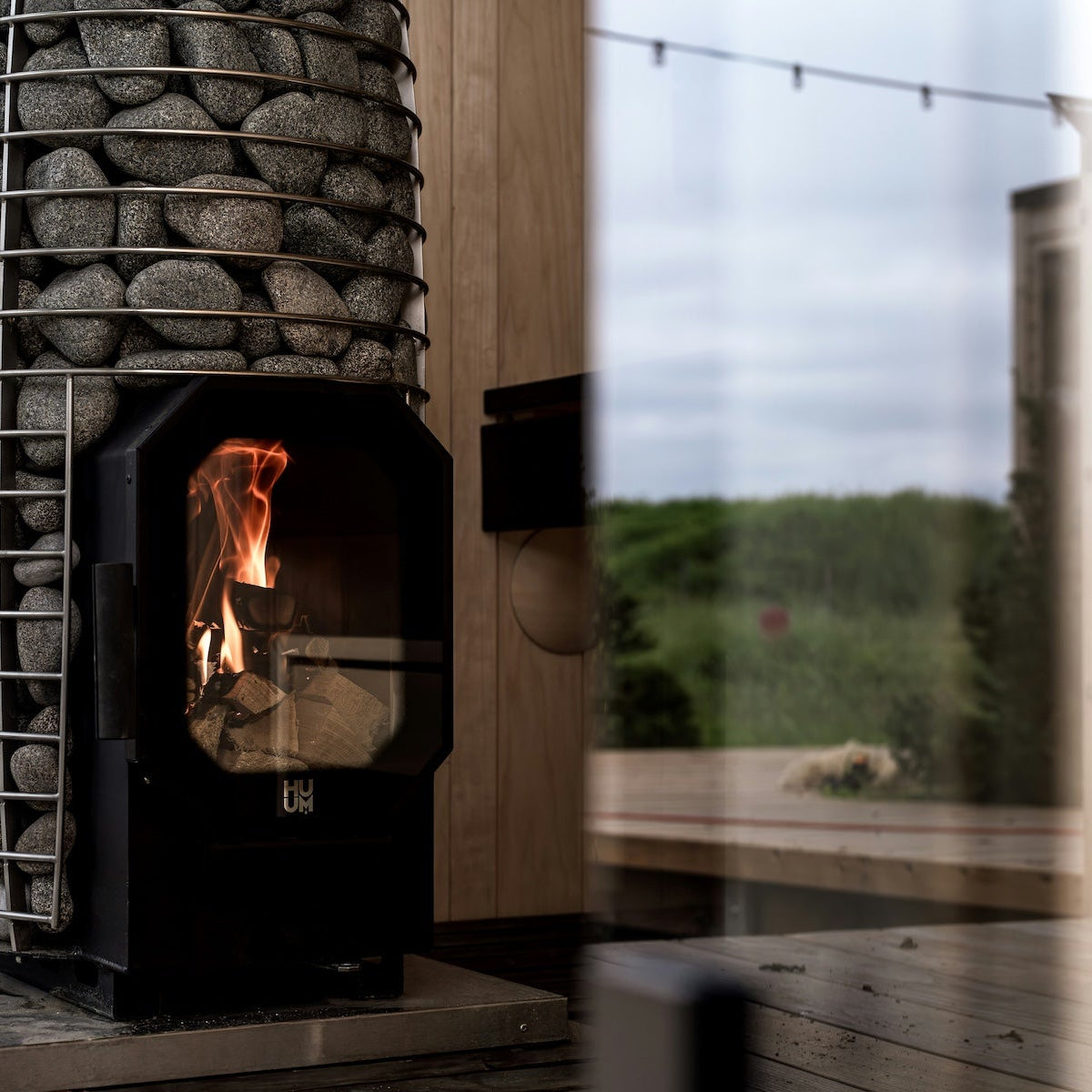 Close-up van een HUUM houtgestookte saunakachel ingebouwd in een strakke houten sauna.