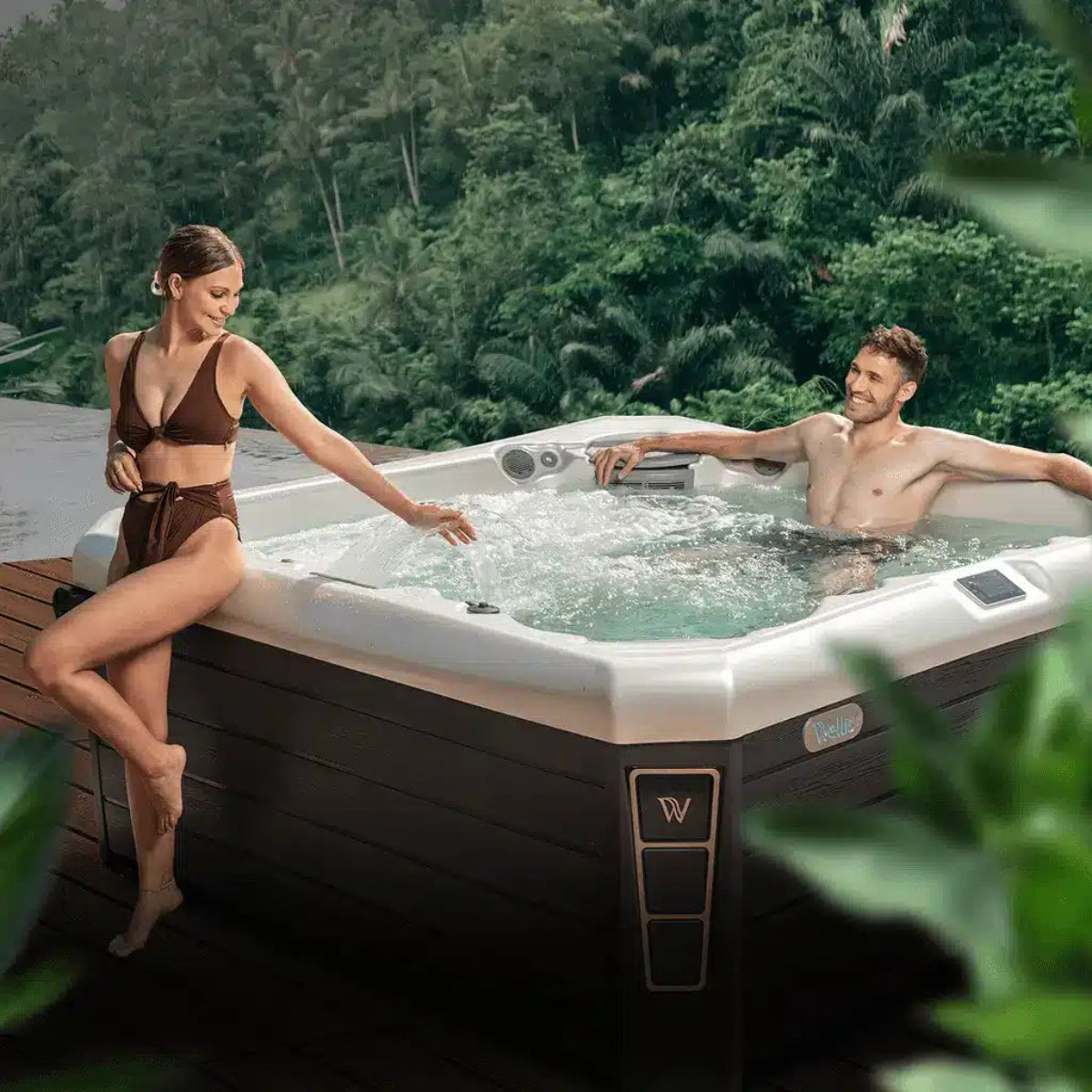 Twee personen ontspannen in een luxe hottub van Wellis in een natuurlijke tuinsetting.